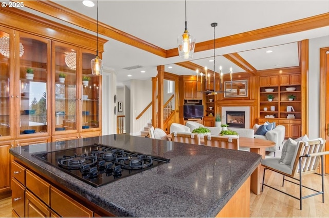 carpeted living room featuring stairs, a large fireplace, ornamental molding, beam ceiling, and built in shelves