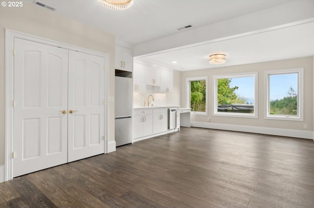 laundry area with stacked washer and clothes dryer, wood-type flooring, plenty of natural light, and recessed lighting