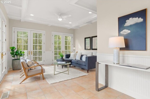 living room with a wainscoted wall, coffered ceiling, tile patterned floors, french doors, and beamed ceiling