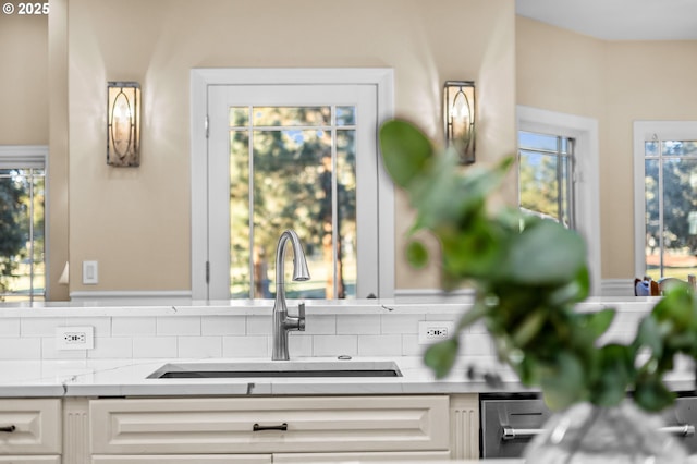 kitchen with tasteful backsplash, a sink, and white cabinets