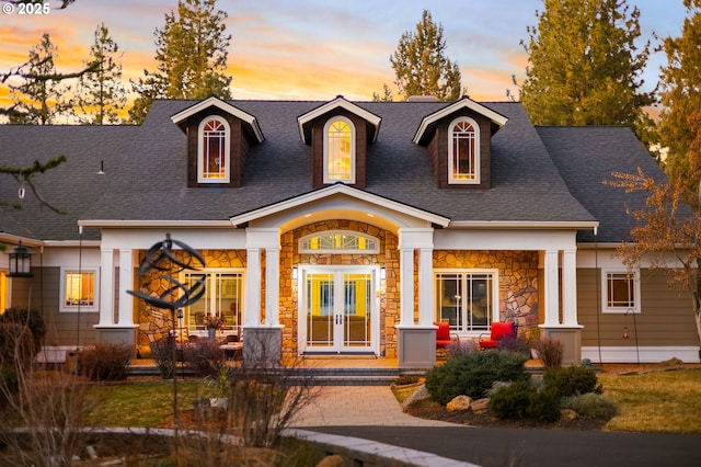 view of front of home featuring stone siding and roof with shingles