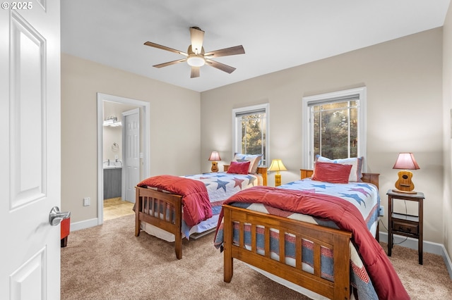 bedroom featuring baseboards, ensuite bathroom, and light colored carpet