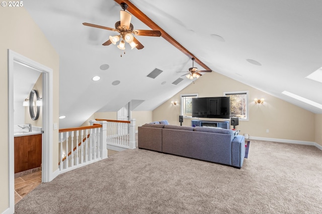 carpeted living room featuring ceiling fan, vaulted ceiling with skylight, visible vents, and baseboards