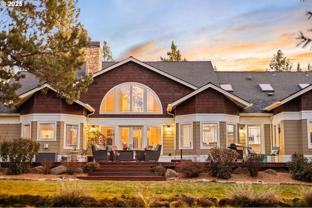 back of house with roof with shingles, a yard, a chimney, and an outdoor living space