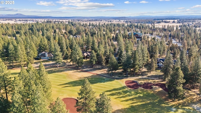 bird's eye view featuring a mountain view, golf course view, and a view of trees