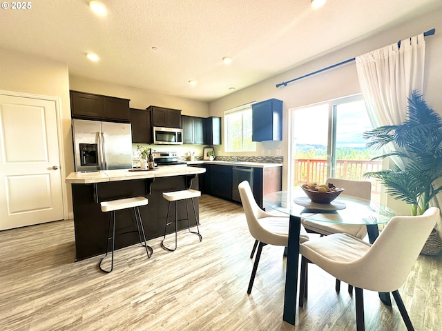 12958 SE 156th Ave, Happy Valley, OR 97086 - kitchen with appliances with stainless steel finishes, a kitchen island, a kitchen breakfast bar, light wood-style flooring, and recessed lighting