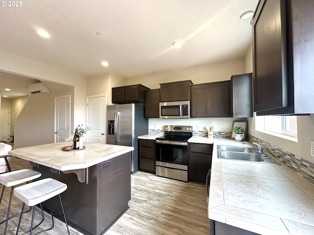12958 SE 156th Ave, Happy Valley, OR 97086 - kitchen with appliances with stainless steel finishes, a sink, dark brown cabinets, recessed lighting, and a kitchen breakfast bar