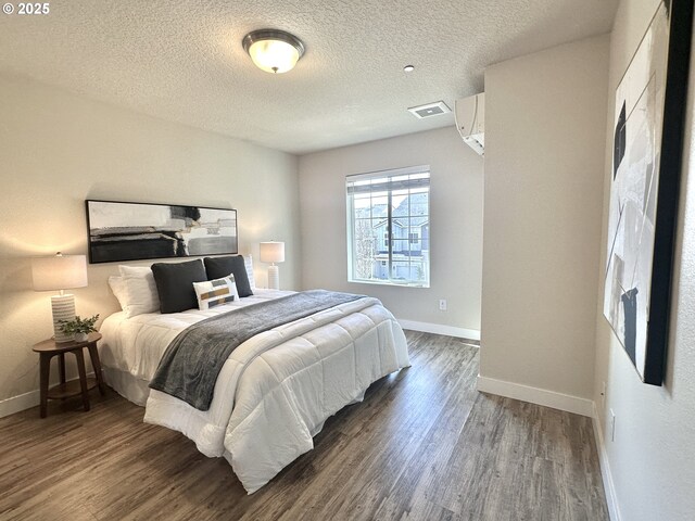 bedroom with dark wood-type flooring, visible vents, a textured ceiling, and baseboards