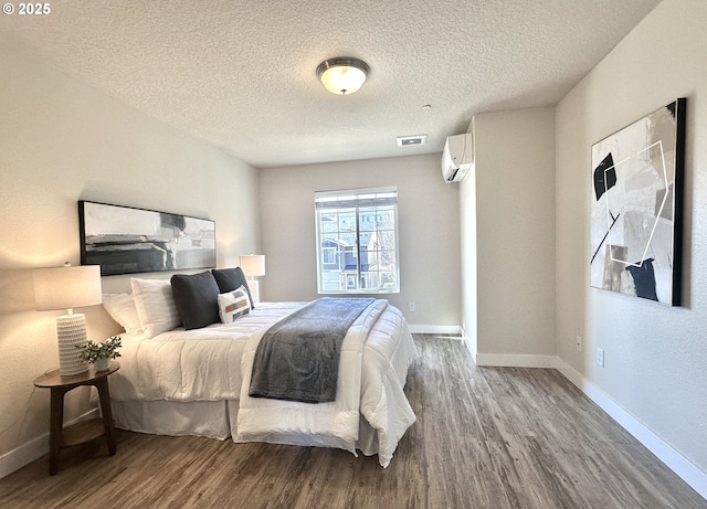 bedroom featuring baseboards, wood finished floors, and a wall mounted air conditioner