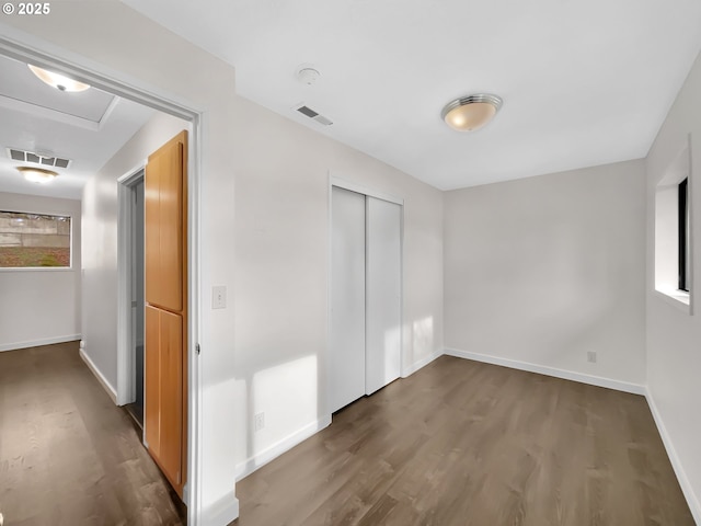 unfurnished bedroom featuring baseboards, a closet, visible vents, and wood finished floors