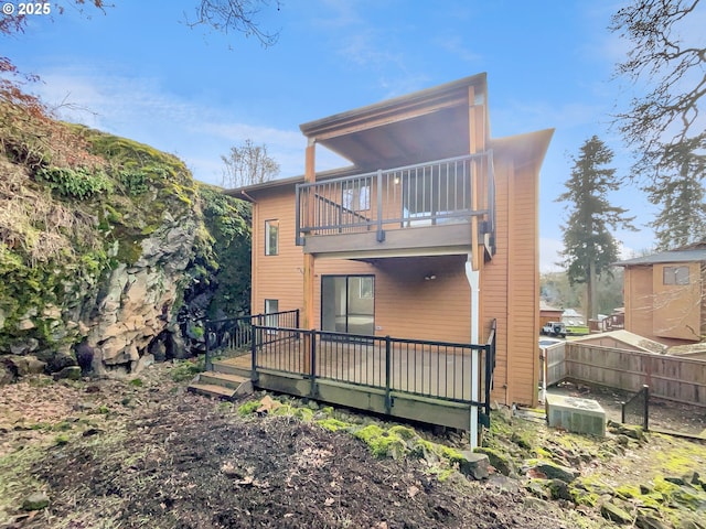 rear view of house featuring fence and a balcony