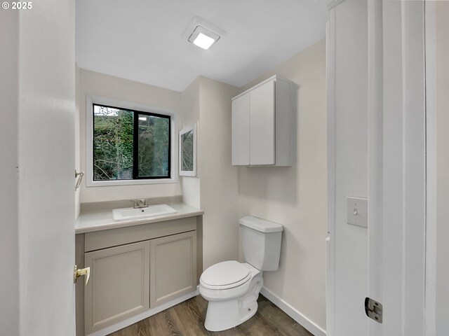 bathroom featuring vanity, wood finished floors, toilet, and baseboards