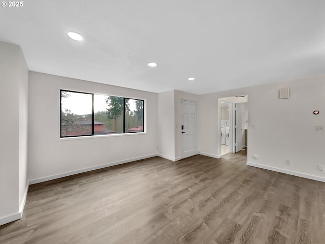 empty room with washer / dryer, baseboards, wood finished floors, and recessed lighting