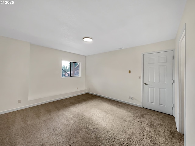 carpeted spare room with visible vents and baseboards