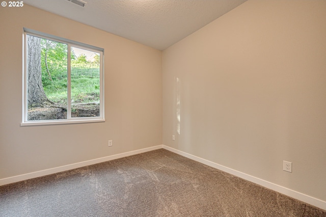 spare room with dark carpet, baseboards, vaulted ceiling, and a textured ceiling