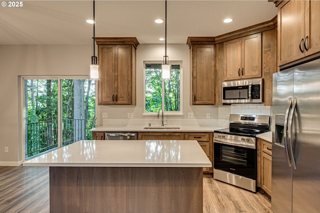 kitchen with stainless steel appliances, a sink, light wood finished floors, light countertops, and recessed lighting