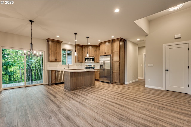 kitchen featuring appliances with stainless steel finishes, light wood-type flooring, a center island, a chandelier, and recessed lighting