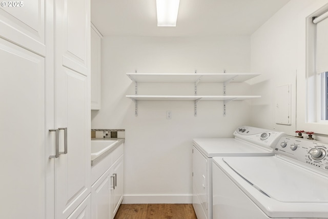 laundry area with sink, cabinets, washing machine and dryer, and wood-type flooring