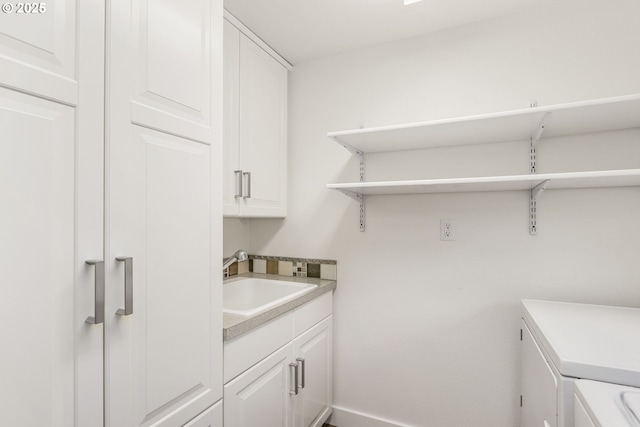 laundry room featuring cabinets, separate washer and dryer, and sink