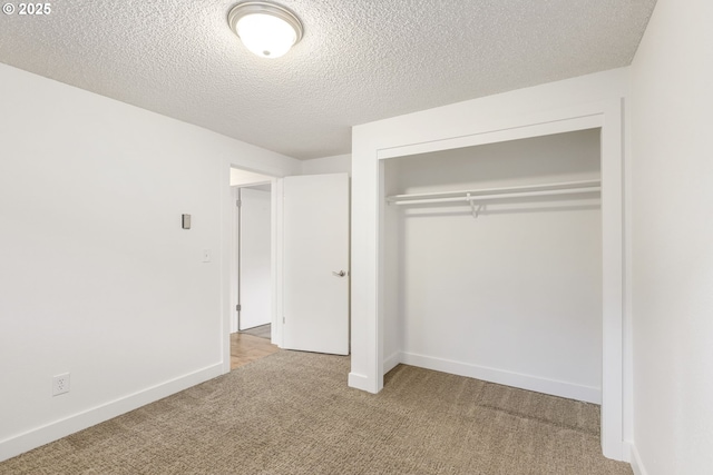 unfurnished bedroom with light colored carpet, a closet, and a textured ceiling