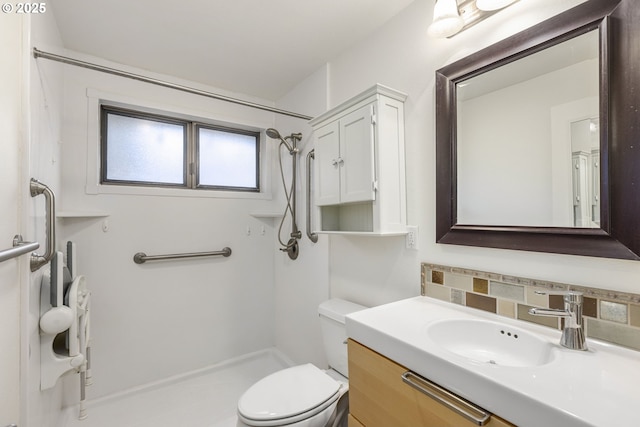 bathroom featuring a shower, backsplash, vanity, and toilet