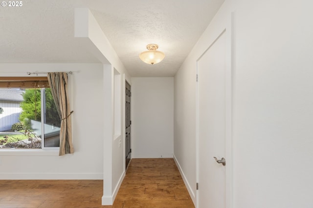 corridor with wood-type flooring and a textured ceiling