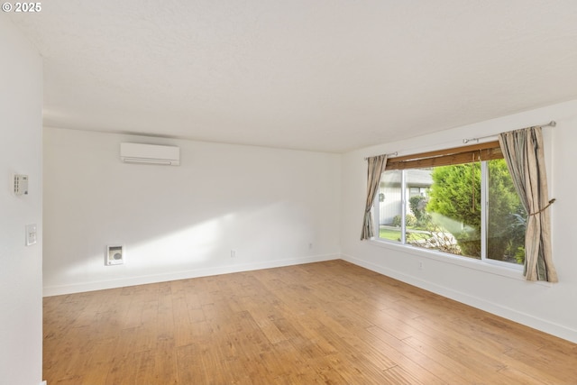 spare room with a wall mounted air conditioner and wood-type flooring