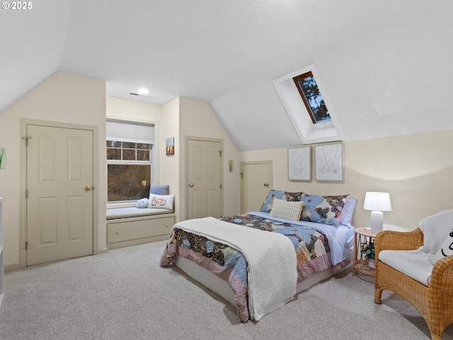 carpeted bedroom featuring vaulted ceiling with skylight