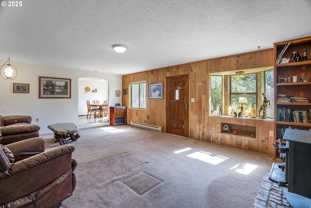 19587 NW Adcock Rd, Yamhill, OR 97148 - carpeted living room featuring a baseboard heating unit, arched walkways, wooden walls, and a textured ceiling