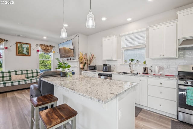 7623 SE Roaring Ln, Hillsboro, OR 97123 - kitchen with stainless steel appliances, backsplash, a kitchen breakfast bar, light wood-style flooring, and recessed lighting