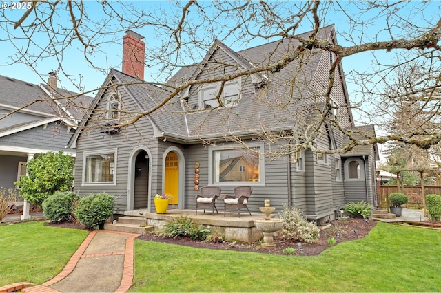 view of front of property with a chimney, a front yard, and fence