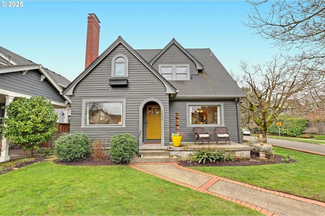 view of front of property featuring a front lawn, roof with shingles, and a chimney