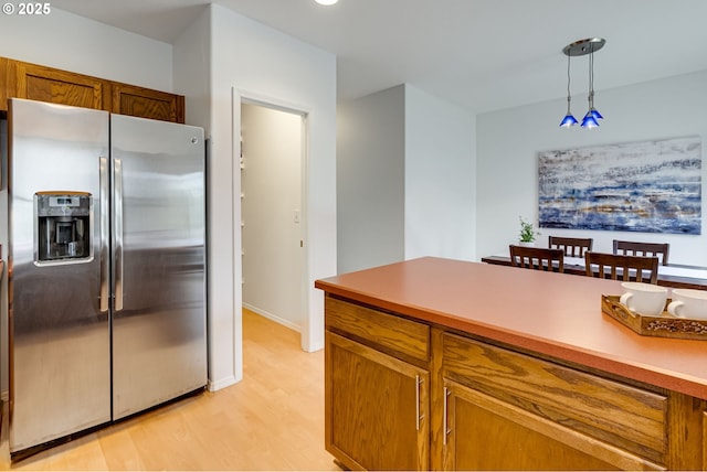 kitchen featuring pendant lighting, light wood-type flooring, and stainless steel fridge with ice dispenser