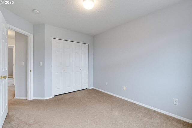 unfurnished bedroom with light carpet, a closet, and a textured ceiling