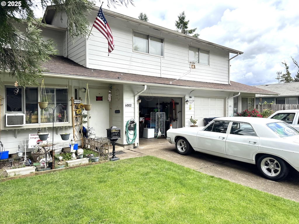 multi unit property featuring an attached garage, a front yard, concrete driveway, and a shingled roof