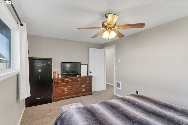 carpeted bedroom with ceiling fan and a textured ceiling