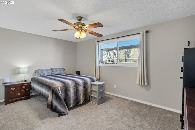 bedroom featuring ceiling fan, light colored carpet, and a textured ceiling