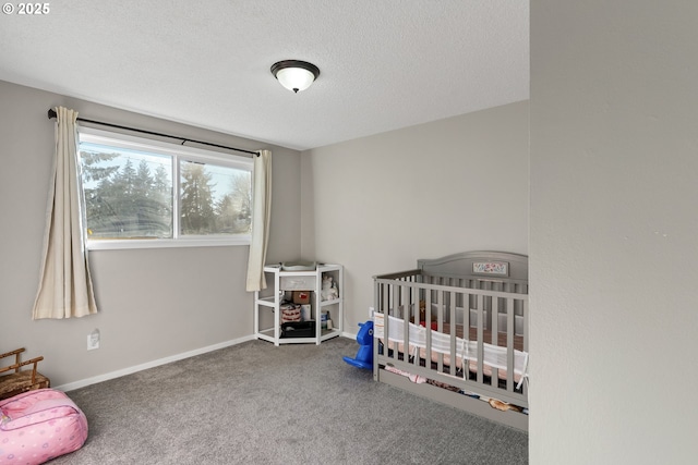 bedroom featuring a nursery area, carpet flooring, and a textured ceiling