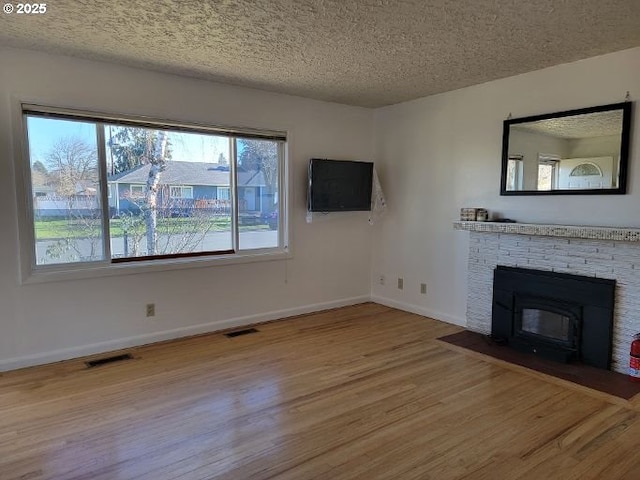 unfurnished living room featuring hardwood / wood-style flooring, a fireplace, and a textured ceiling