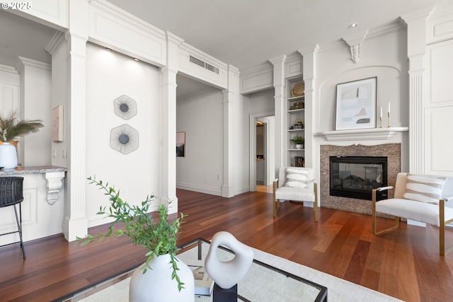 living room featuring crown molding, baseboards, decorative columns, and wood finished floors