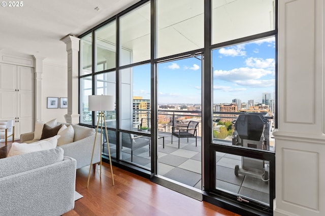 doorway to outside featuring ornate columns, floor to ceiling windows, a wealth of natural light, and dark wood-type flooring