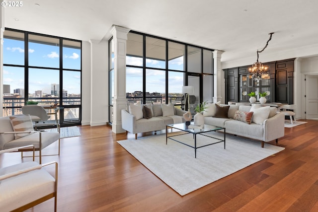living area featuring a notable chandelier, a wealth of natural light, expansive windows, and wood finished floors