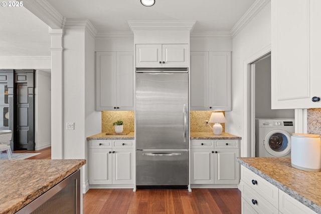 kitchen with washer / clothes dryer, decorative backsplash, dark wood finished floors, and stainless steel built in fridge