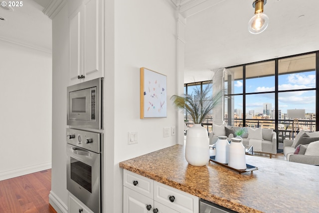 kitchen with a wall of windows, a city view, dark wood-style floors, ornamental molding, and stainless steel appliances