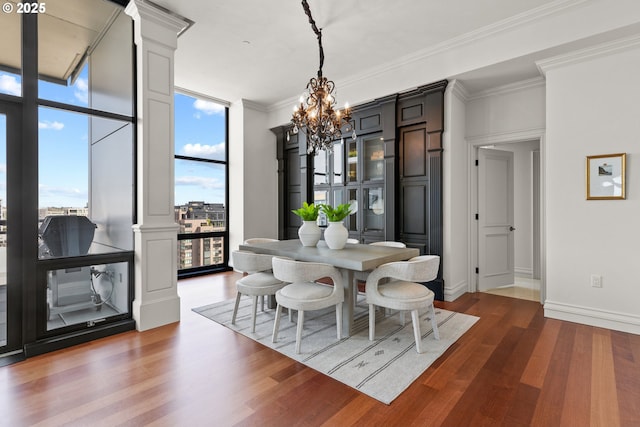 dining area with decorative columns, wood finished floors, baseboards, an inviting chandelier, and ornamental molding