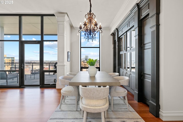 dining space featuring ornate columns, ornamental molding, a chandelier, and dark wood-style floors