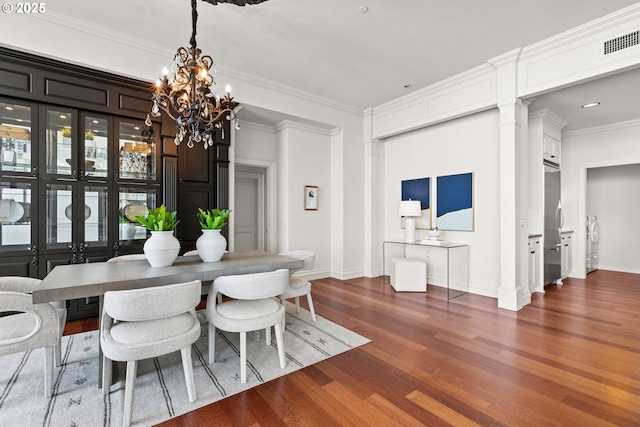 dining area with visible vents, ornamental molding, an inviting chandelier, baseboards, and dark wood-type flooring