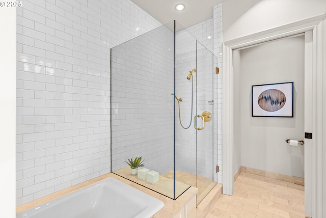 bathroom featuring baseboards, a shower stall, a garden tub, and recessed lighting