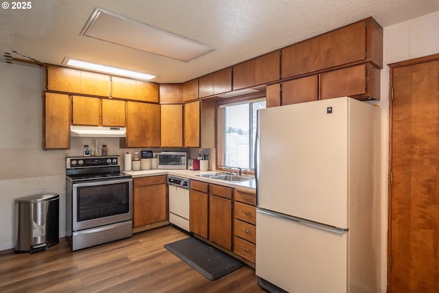 kitchen featuring sink, white appliances, light hardwood / wood-style floors, and a textured ceiling