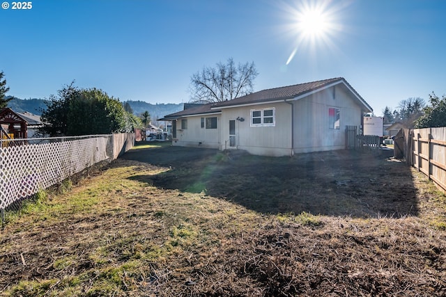 rear view of house featuring a mountain view and a yard